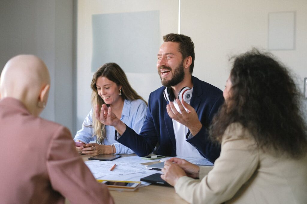 Happy group of colleagues talking and sharing opinions at table in conference in business office